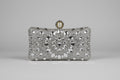 Silver clutch bag with intricate design and pearl clasp